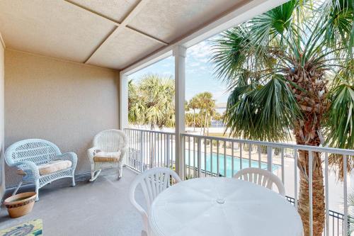 a balcony with a table and chairs and a palm tree at Grand Caribbean Perdido Key 211 EAST in Pensacola