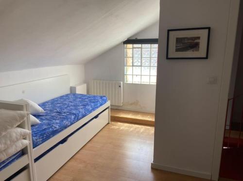 um quarto com uma cama com um edredão azul e uma janela em Ático dúplex en Monte Gorbea em Serra Nevada