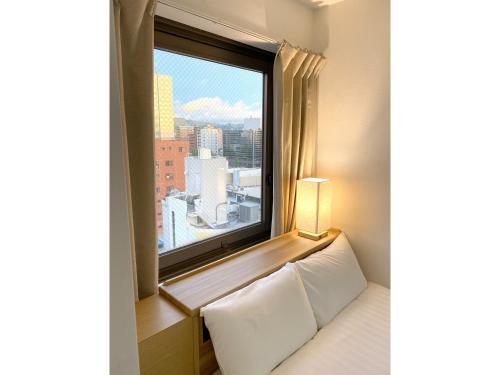 a room with a window with a white bed and a window sill at Santiago Hotel - Vacation STAY 74128v in Hiroshima