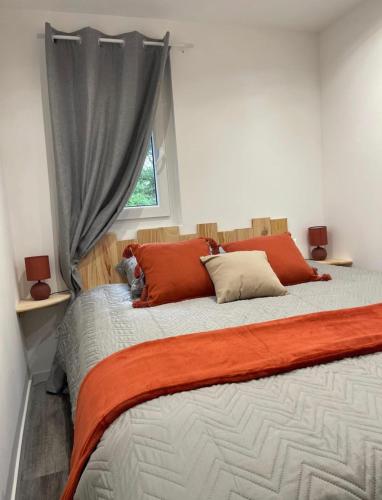 um quarto com uma cama com almofadas laranja e uma janela em Charmant chalet cocooning avec Jacuzzi em Arthon