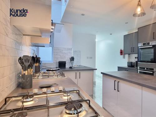 a large kitchen with a stove top oven in it at Kunda House Croydon in Birmingham