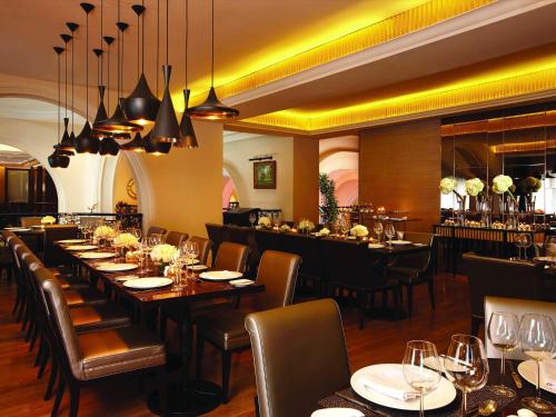 a restaurant with long tables and chairs and a bar at Hotel Gran Mahakam in Jakarta