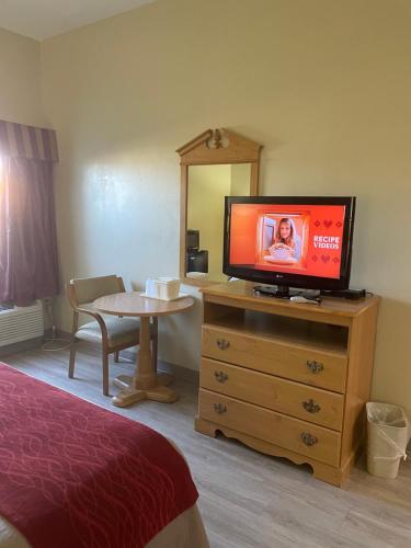 a room with a television on a dresser with a table at Econo Lodge Newport West in Newport