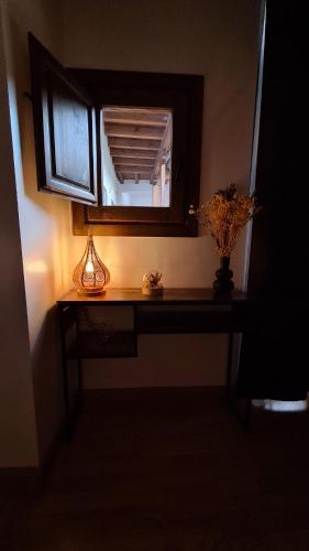 a table with a mirror and a vase with flowers on it at El Rinconcito de la Merced in Toledo