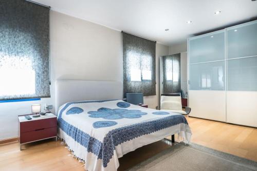 een slaapkamer met een bed met een blauwe en witte deken bij ¡Impactante apartamento a cero linea de mar! in Tarragona