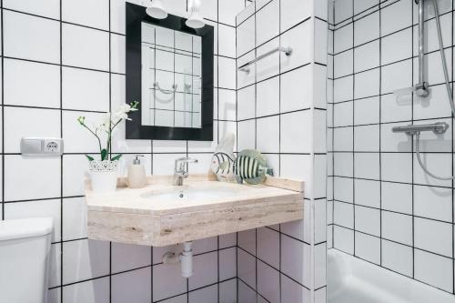 a white bathroom with a sink and a mirror at ¡Impactante apartamento a cero linea de mar! in Tarragona