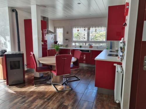 a kitchen with red cabinets and a table and chairs at Appartement chaleureux et confortable avec sauna.. in Le Chenit