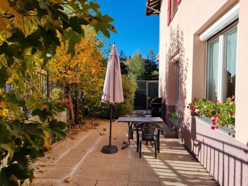 a patio with an umbrella and a table and chairs at Appartement chaleureux et confortable avec sauna.. in Le Chenit