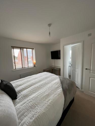 a white bedroom with a large bed and a television at Hawk House - Furnished Accommodation in Hatfield