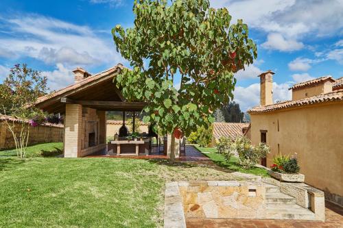 a patio with a table and a tree in a yard at Hacienda el Potrero - Un lugar para siempre recordar in Suesca