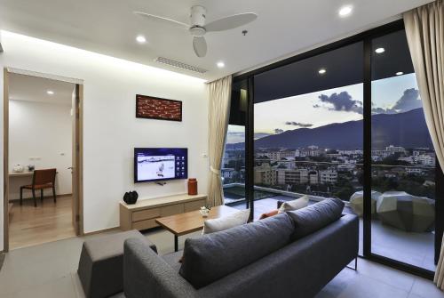a living room with a couch and a large window at Eastin Tan Hotel Chiang Mai in Chiang Mai