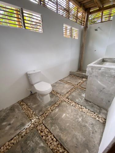 a bathroom with a toilet and a stone floor at Playa Jaguar - Beach Club in Moñitos
