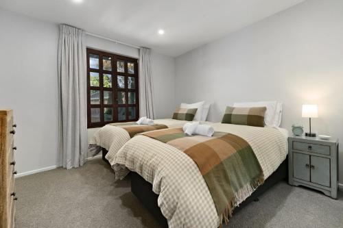 a white bedroom with two beds and a window at Alpine Cottage in Queenstown
