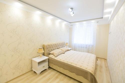 a bedroom with a bed and a white wall at White Sky Apartment in Chişinău