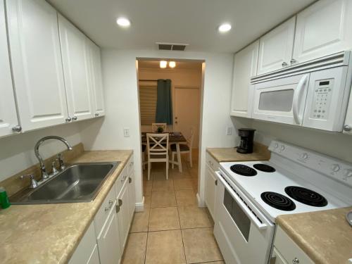 a kitchen with white cabinets and a sink and a stove at Bayview Regency Apartments By Lowkl in Fort Lauderdale