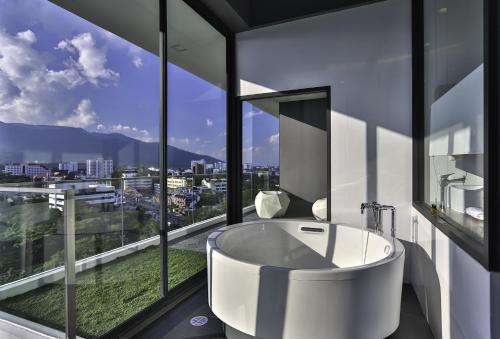 a bathroom with a tub and a large window at Eastin Tan Hotel Chiang Mai in Chiang Mai