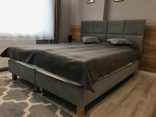a bedroom with a large bed with a large headboard at Rybacka 48 - Twoje miejsce wypoczynku, domki, studia, apartamenty, rowery, hulajnogi in Jantar