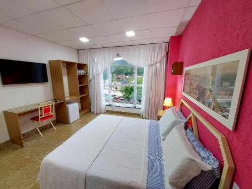 a bedroom with a large bed and a pink wall at Hotel Netto in Cachoeiras de Macacu