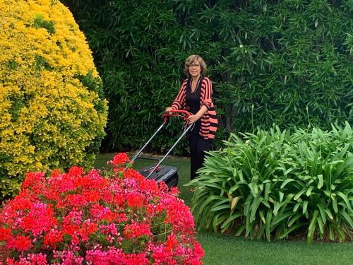 a woman with a suitcase in a garden with flowers at Arenosu Comfort Country Guesthouse in Fertilia