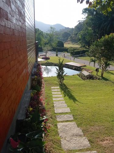a stone walkway next to a building with a pond at Pousada e Restaurante Casa Cida e Evandro in Gaspar