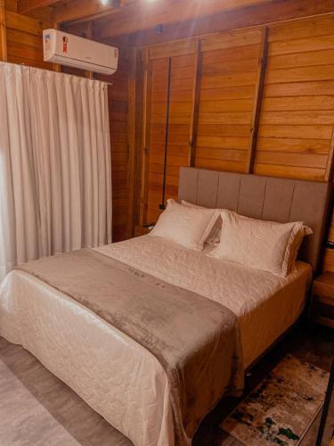 a bed in a room with wooden walls and ceilings at Pousada e Restaurante Casa Cida e Evandro in Gaspar