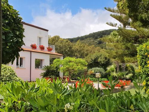 a house with a garden with flowers and trees at Arenosu Comfort Country Guesthouse in Fertilia