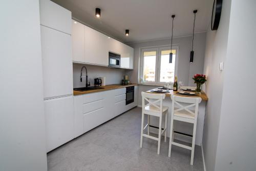 a white kitchen with white cabinets and white stools at Apartament KOPERNIK w centrum in Iława