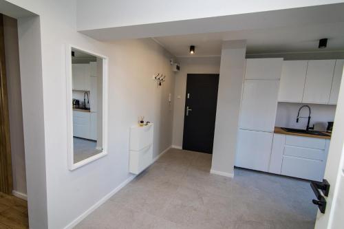 a kitchen with white cabinets and a mirror at Apartament KOPERNIK w centrum in Iława
