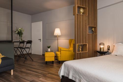 une chambre d'hôtel avec un lit et une chaise jaune dans l'établissement K-Houses A4, à Árta