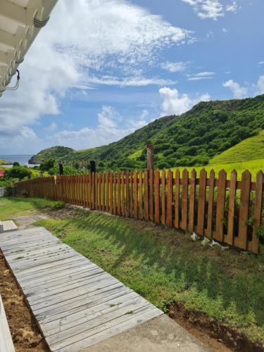 una recinzione di legno con una collina sullo sfondo di Chez Gisèle et Philippe a Terre-de-Haut