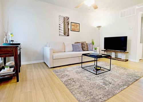 a living room with a white couch and a tv at Global Cup Dwell By Design & Arboretum Tickets Included in Dallas