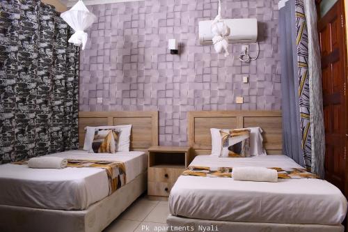 een slaapkamer met 2 bedden en een muur met tegels bij PK Ocean A3 in Mombasa