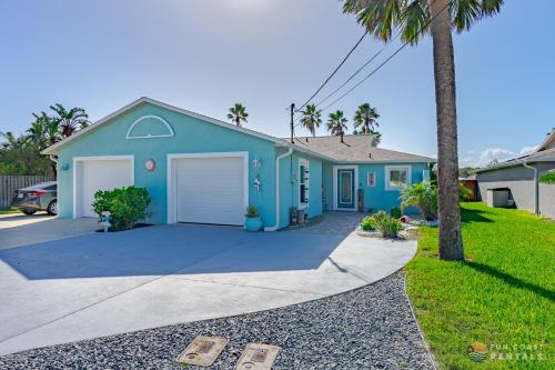 uma casa azul com palmeiras em frente em Relaxing Beach Home with Fire Pit and Private Fenced Yard STEPS from the Sand! em New Smyrna Beach