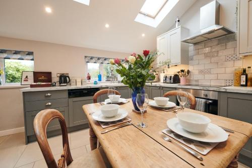a kitchen with a wooden table with chairs and flowers at Goilan Goch in Llandeilo