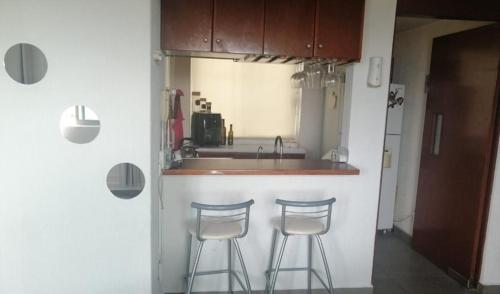 a kitchen with three bar stools and a sink at Departamento céntrico y excelente vista a ciudad in Mexico City