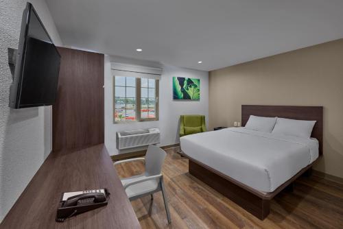 奇瓦瓦的住宿－Extended Suites Chihuahua La Juventud，一间卧室配有一张床、一台电视和一张书桌
