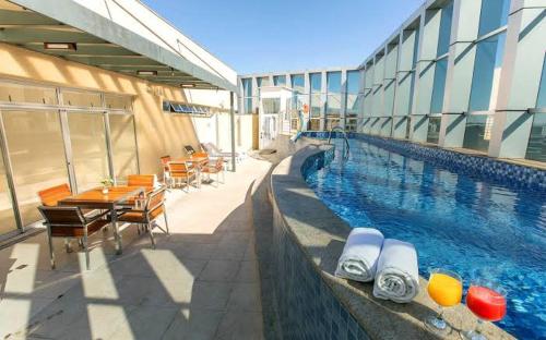 a swimming pool with tables and chairs next to a building at Flat Setor de Hotéis Norte no Hotel Fusion in Brasilia