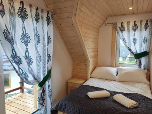 a bed in a tiny house with a window at Mały Zakątek Dzianisz "Balia na wyłączność" in Dzianisz
