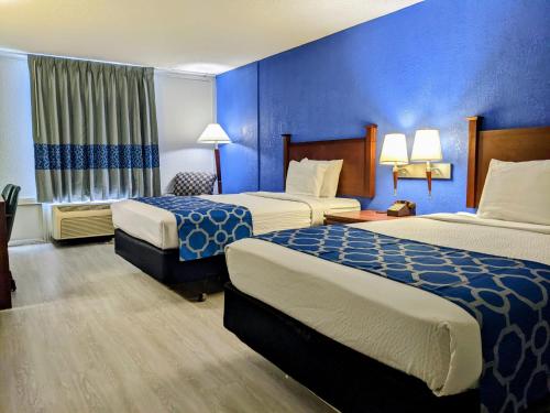 a hotel room with two beds and a blue wall at Baymont by Wyndham Hannibal in Hannibal
