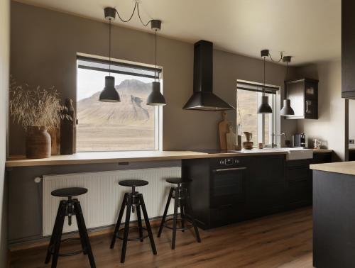 a kitchen with black cabinets and a counter with stools at Klöpp Lodge - Snæfellsnes Peninsula in Stykkishólmur
