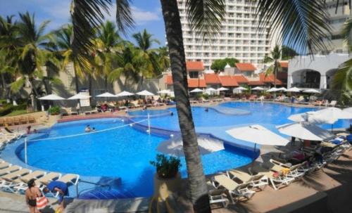 a large swimming pool with chairs and umbrellas at a hotel at Villa 19 Con Playa 2 Recamaras dentro de Hotel en Ixtapa in Ixtapa
