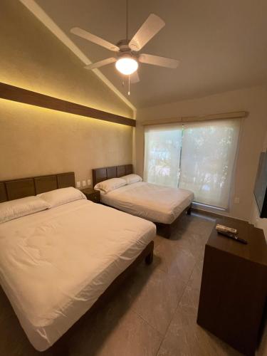 a bedroom with two beds and a ceiling fan at Villa 19 Con Playa 2 Recamaras dentro de Hotel en Ixtapa in Ixtapa