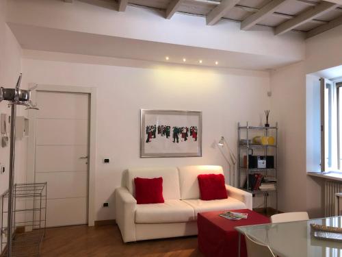 uma sala de estar com um sofá branco e almofadas vermelhas em Emma Home adiacente alla Piazza Ducale em Vigevano