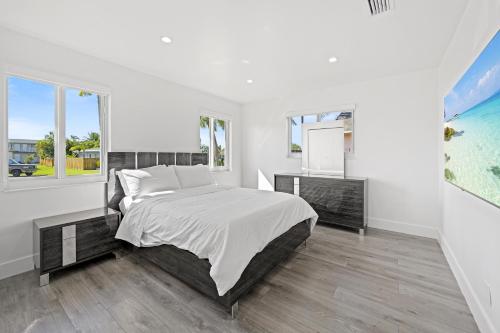 a white bedroom with a large bed and two windows at Private Spacious House #BBQ - Hallandale Beach, Florida in Hallandale Beach