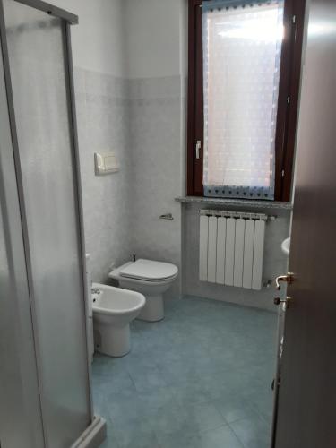 biała łazienka z toaletą i oknem w obiekcie Appartamento Sofia w mieście Carbonara al Ticino