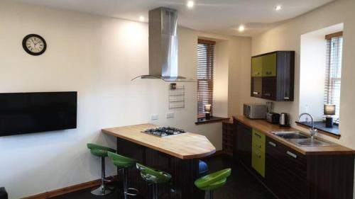 a kitchen with a sink and a counter with green stools at Ensuite Rooms in Wick