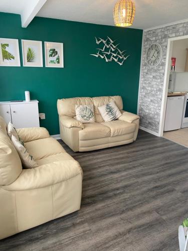a living room with two couches and a green wall at East Coast Chalets 58 at California Sands Dog Friendly in Great Yarmouth