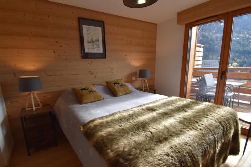 a bedroom with a bed and a large window at VAUJANYLOCATIONS - L'Etendard in Vaujany