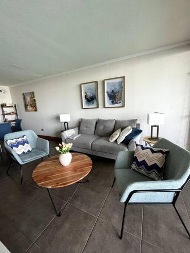 a living room with a couch and two chairs and a table at apartamento con vista al mar y piscina. in Iquique
