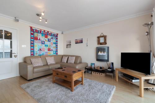 a living room with a couch and a flat screen tv at On The Beach - Direct Beach Access Sea Views in Saundersfoot